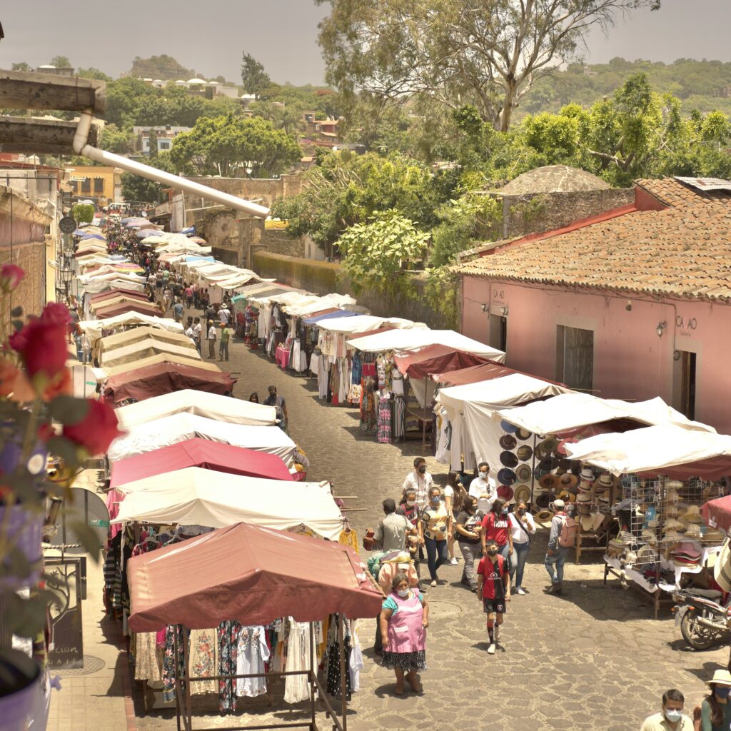 Street vendors on a cobble stoned street with trees in the background in a town called Tepoztlan, Mexico